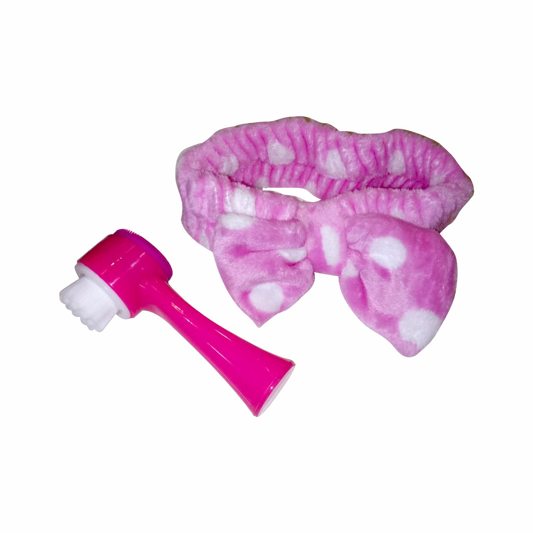 A pink and white dotted headband alongside a pink and white dual-sided facial cleansing brush.